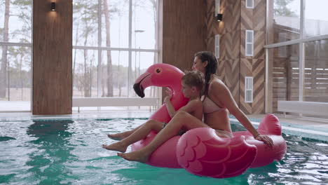 family-weekend-in-water-park-mother-with-child-are-floating-on-inflatable-pink-flamingo